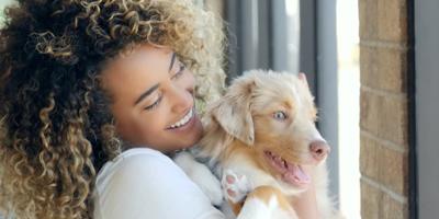 woman with curly hair holding a dog
