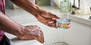 washing a friskies tin under water