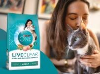 owner kissing a cat that's sitting next to a bag of Purina ONE liveclear dry cat food