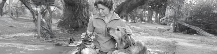 girl petting her dog and cat in a park